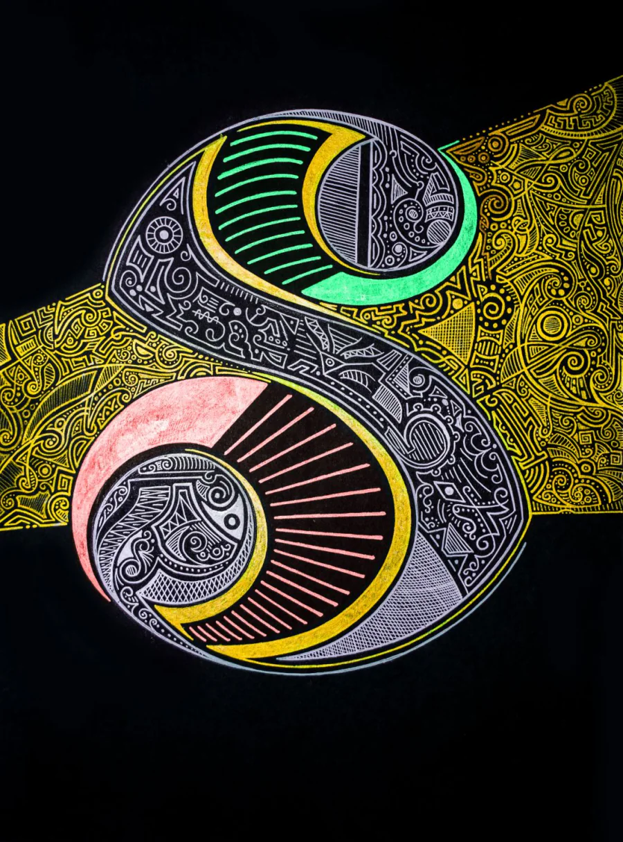 A single ornamented capital S in silver with golden, green and coral, on black paper.